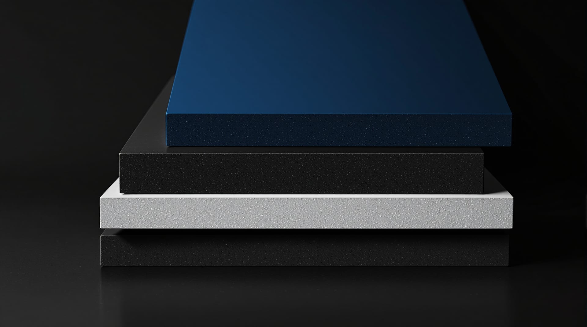 Offset stack of flat cut card slabs in black, blue and grey showing bevelled cut edges